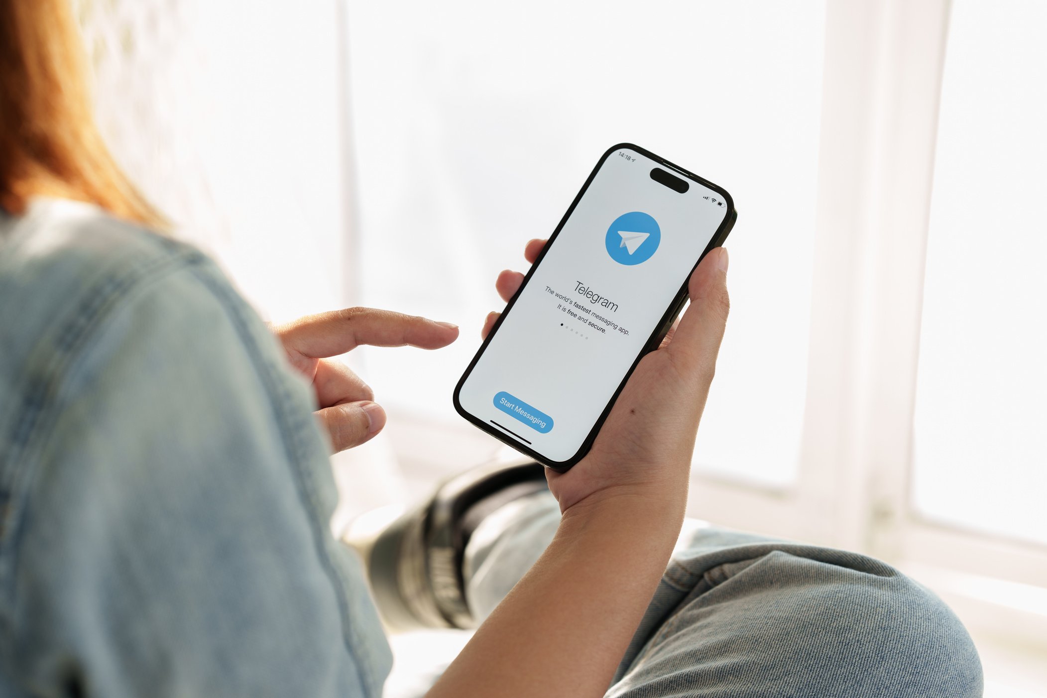 CHIANG MAI, THAILAND, FEB 12, 2023 : Woman hand using iPhone 14 with social networking service Telegram on the screen. Close up woman holding iPhone